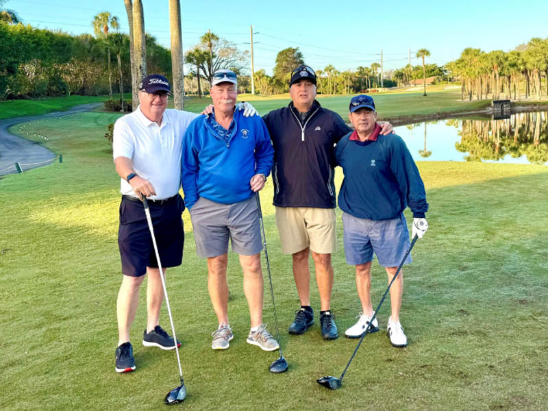 Four male golfers stand on the golf grounds